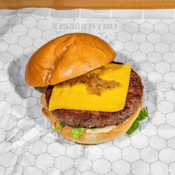 Taylor Gourmet cheeseburger with melted cheese, caramelized onions, lettuce, and sauce on a bun.