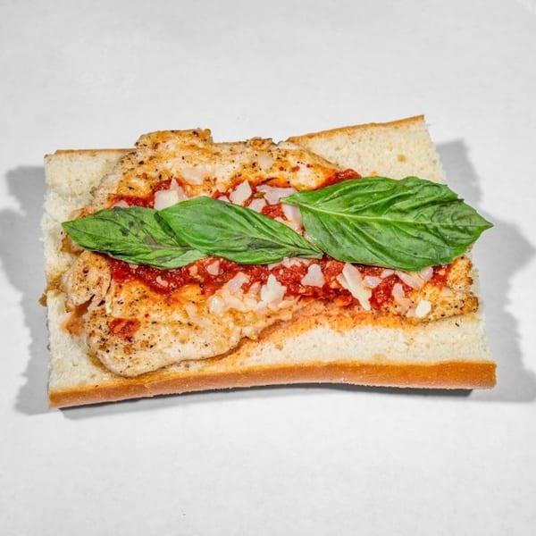 Taylor Gourmet's chicken parmesan sandwich with basil, marinara, and cheese on a white background.