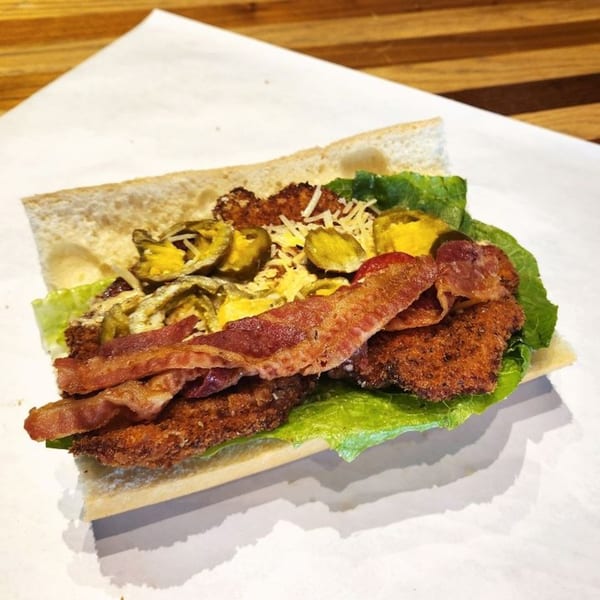Taylor Gourmet sandwich with fried chicken, bacon, lettuce, pickled jalapeños, and cheese on a sub roll.